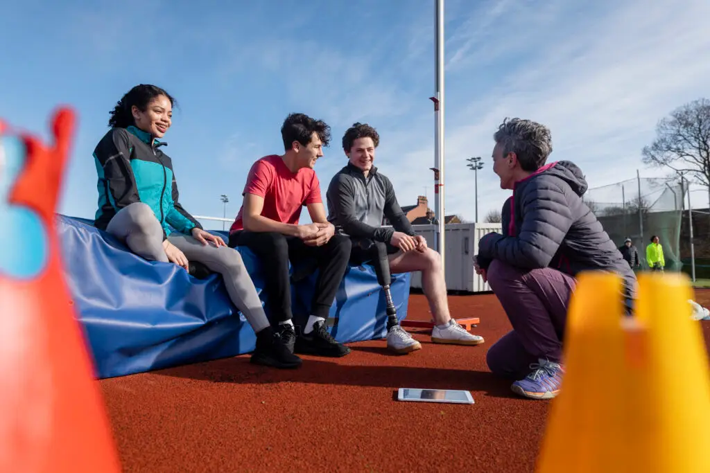 A young group of athletes sitting down and sharing a discussion with their coach.