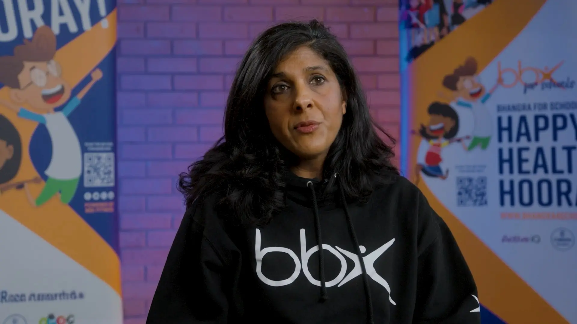 Group exercise instructor sat talking to camera.