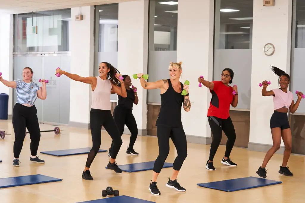 A group of women taking part in an exercise class using small weights