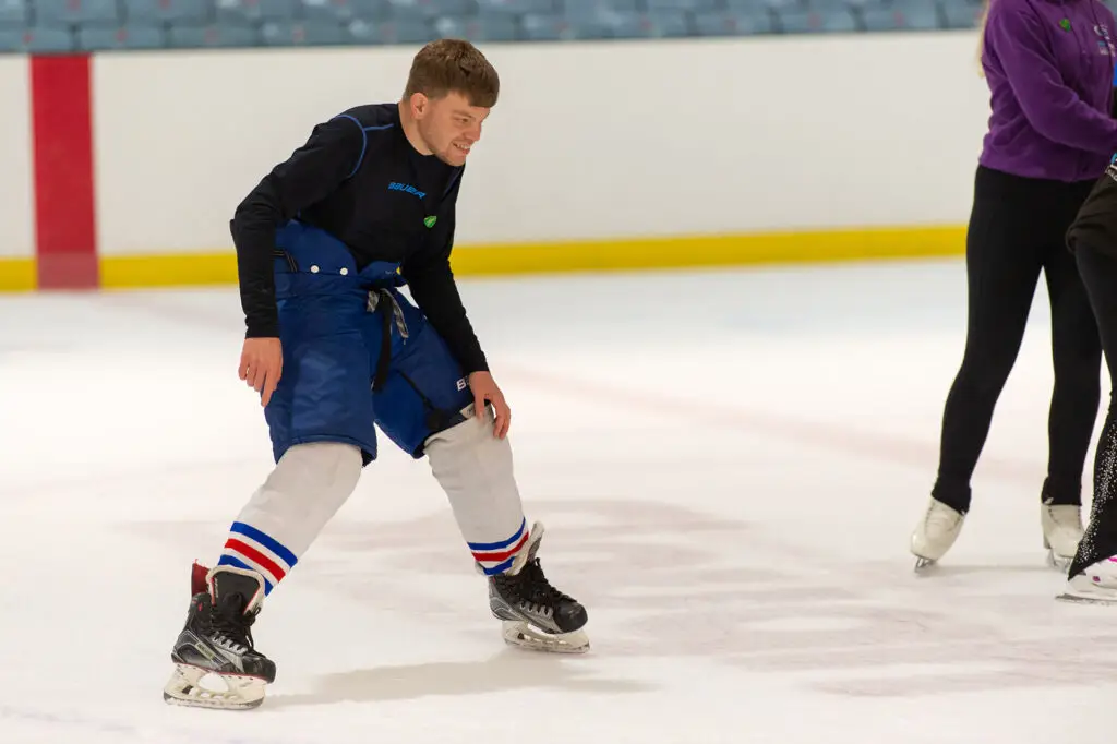 A neurodiverse person ice skating in an indoor rink