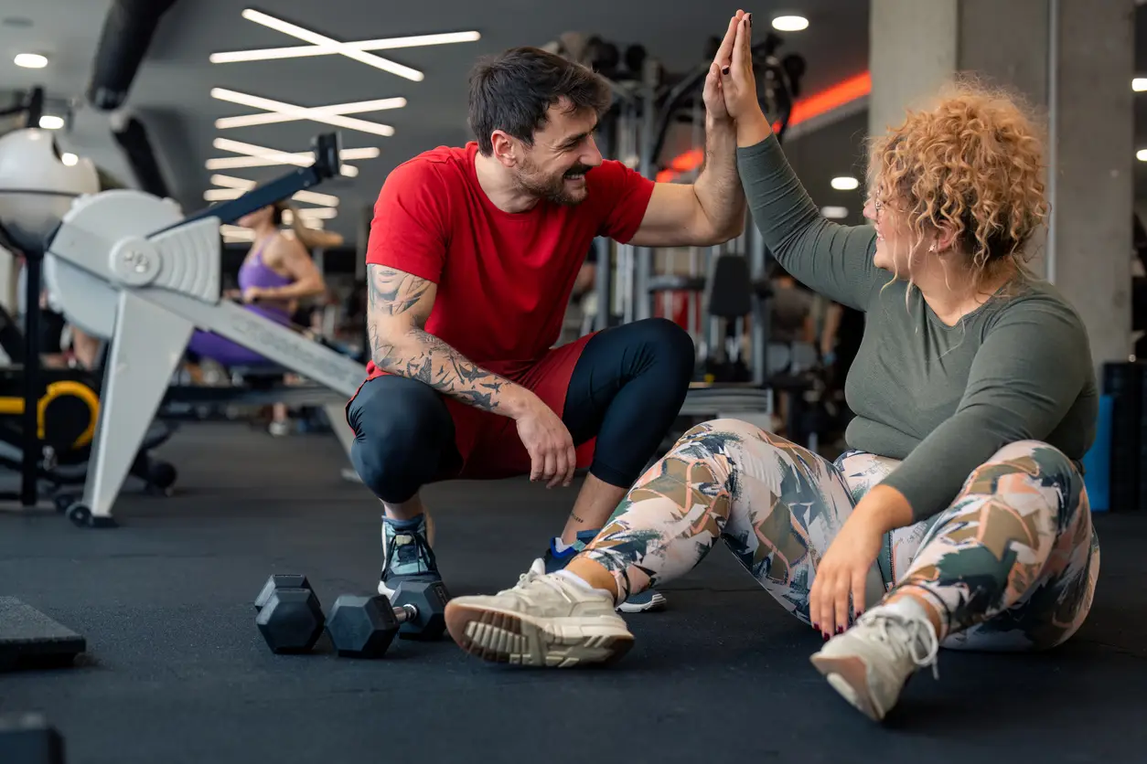 Personal trainer giving a client a high-five in a gym